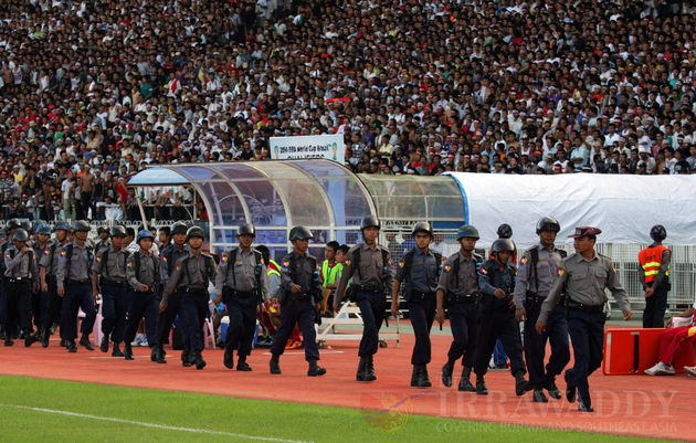 Burmese police officers walk into the field.
