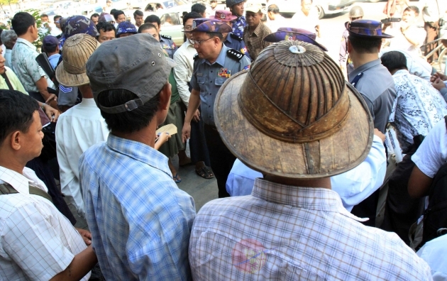 A Myanmar police  man talks with a farmer protester during a rally against the government in downtown Yangon Thursday, Oct.27, 2011, in Yangon, Myanmar