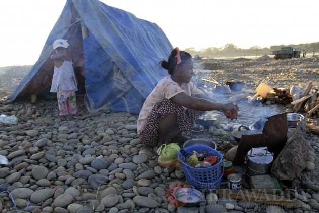 A woman of Burma's Kachin national race prepares their meal near a make-shift tent as other family members pan for gold in a river in Myitkyina, Kachin State, about 1,600 km (1,000 miles) north of Rangoon, Burma. A woman of Burma's Kachin national race prepares their meal near a make-shift tent as other family members pan for gold in a river in Myitkyina, Kachin State, about 1,600 km (1,000 miles) north of Rangoon, Burma.