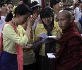 The leader of National League for Democracy (NLD) Aung San Suu Kyi gives alms to monks in Rangoon, Burma.
