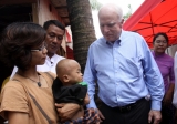 U.S. Senator John McCanin (Right) greets a child carrying HIV virus during his visit to Burma AIDS activist Phyu Phyu Thin's shelter for AIDS patients in Rangoon, Burma.
