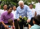 U.S. Senator John McCanin  accepts yellow roses from children carrying HIV virus during his visit to the shelter for AIDS patients run by Phyu Phyu Thin , Burma's well-known AIDS activist in Rangoon, Burma.