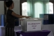 Lady put her ballot in the ballot box at the poll station.