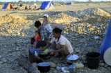 A woman of Burma's Kachin national race prepares their meal near a make-shift tent as other family members pan for gold in a river in Myitkyina, Kachin State, about 1,600 km (1,000 miles) north of Rangoon, Burma.