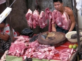 A butcher waits for customers from their road site stall in downtown in Rangoon, Burma.