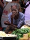 A vendor has a smoke as she sells green groceries on a road in downtown in Rangoon, Burma.