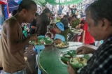 Revelers and passersby enjoy their free lunch in downtown Rangoon on the last day of Thingyan on Sunday when well-wishers host street parties as a part of merit-making during the water festival.     PHOTO - NAING LIN SOE / THE IRRAWADDY